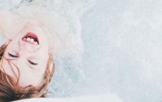 imagem mostra menino em uma piscina sorrindo, explorando os benefícios da natação infantil