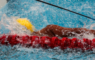 imagem de nadador com deficiência visual com o auxílio de um tapper, acessório permitido pelas regras da natação paralímpica